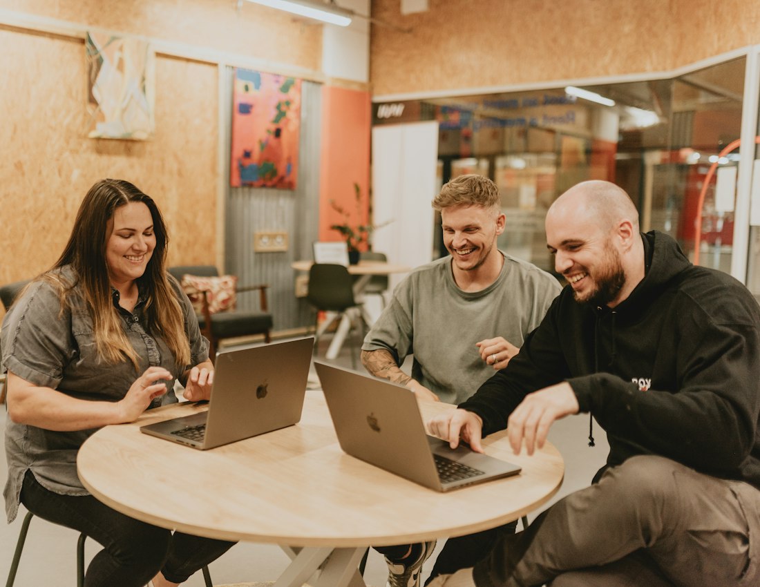 Team laughing while working on laptops